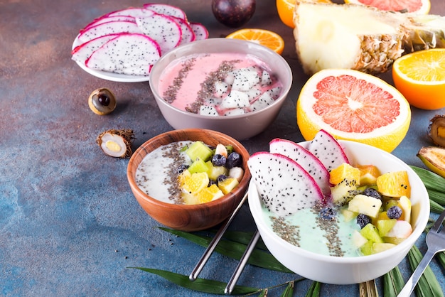 Bol de yaourt vert de petit déjeuner garni de pitaya, ananas, graines de chia et baies à la feuille de palmier sur fond de pierre, vue de dessus Photo Premium