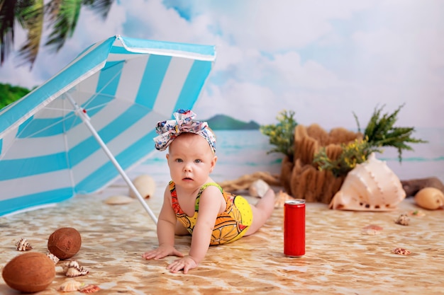 Bonne Petite Fille En Maillot De Bain Des Bains De Soleil Sur Une Plage De Sable Au Bord De La Mer Sous Un Parasol Photo Premium