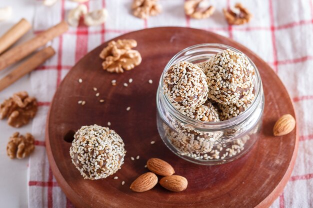 Boules d'énergie gâteaux aux amandes, sésame, noix de cajou, noix, dattes et blé germé dans un bocal en verre, vue latérale, gros plan. Photo Premium