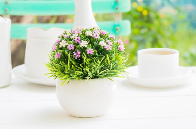 Un bouquet de fleurs en plastique dans un vase sphérique blanc au petit déjeuner. Photo Premium