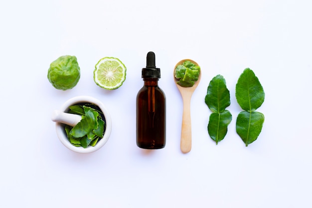Bouteille d'huile essentielle et de limes de kaffir fraîches ou de fruits de bergamote avec des feuilles Photo Premium