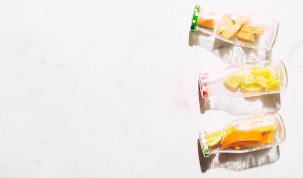 Bouteilles en verre avec des bouchons colorés pleins d'agrumes tranchés Photo gratuit