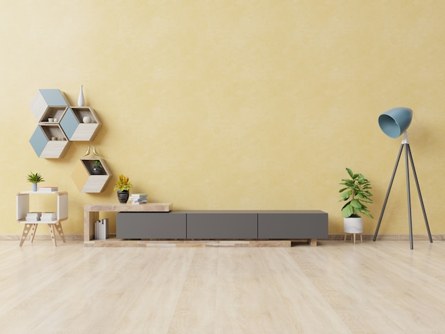 Cabinet pour la télévision ou placer un objet dans le salon moderne avec lampe, table, fleur et plante sur un mur jaune. Photo Premium