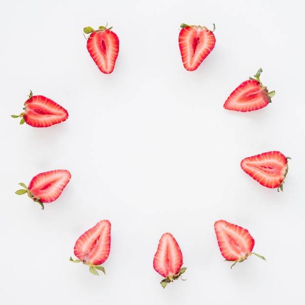 Cadre composé de fraises coupées en deux en cercle sur fond blanc Photo gratuit