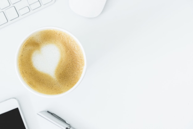Un café au lait avec du coeur d'art sur la table de bureau blanche de la vue de dessus et l'espace de la copie. appartement poser avec concept de bureau, affaires et saint-valentin. Photo Premium
