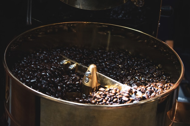 Café torréfié dans le torréfacteur, machine à rôtir les grains de café à rôtir de près Photo Premium