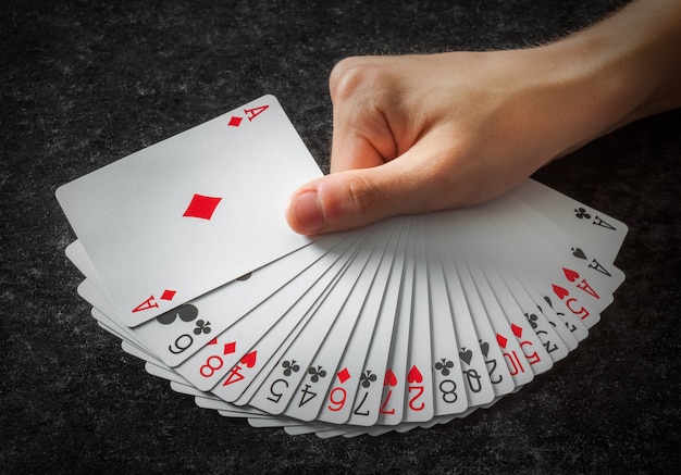 Cartes de poker ouvertes en éventail tenues par une main sur un fond sombre Photo Premium