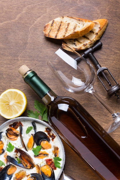Casserole plate avec moules en sauce blanche avec bouteille de vin Photo gratuit
