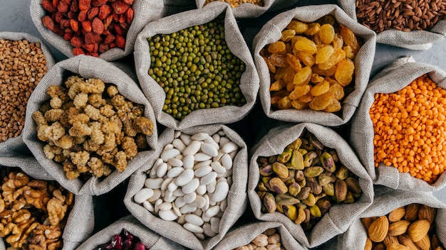 Céréales saines et fruits secs. bouchent la vue de dessus de petits sacs avec des graines de légumineuses sèches. différents types de haricots. grains naturels. Photo Premium