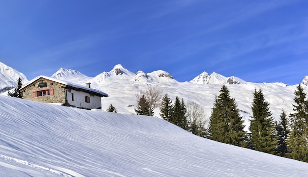 Chalet Dans La Belle Montagne Enneigée Sous Le Ciel Bleu