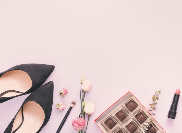 Chaussures de femme avec des cosmétiques et des roses sur la table Photo gratuit