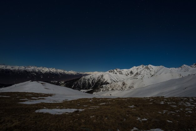 Ciel étoilé vue de nuit sur les alpes. chaîne de montagnes enneigée au clair de lune. Photo Premium