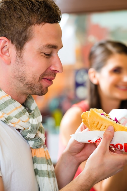 Des clients mangeant du hotdog dans un snack rapide Photo Premium