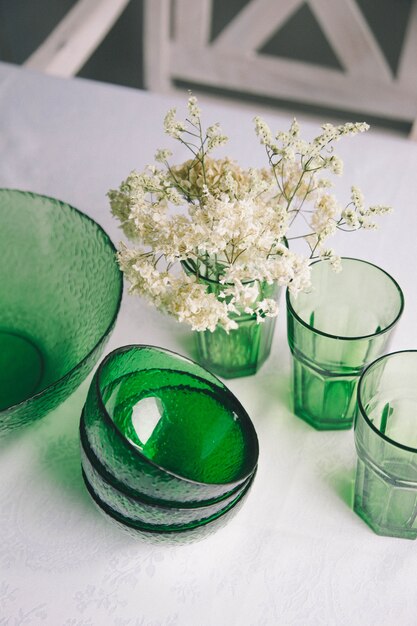 Close-up servant des plats sur une table. plats verts - saladier, assiettes creuses et verres. ils sont décorés d'un petit bouquet de fleurs Photo Premium