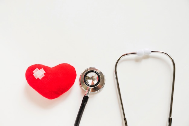 Coeur rouge avec des bandages et stéthoscope sur fond blanc Photo gratuit