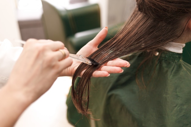 Le coiffeur applique un masque capillaire à la femme dans le salon de