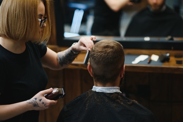 Coiffeur professionnel femme faisant le style de beau mec avec tondeuse