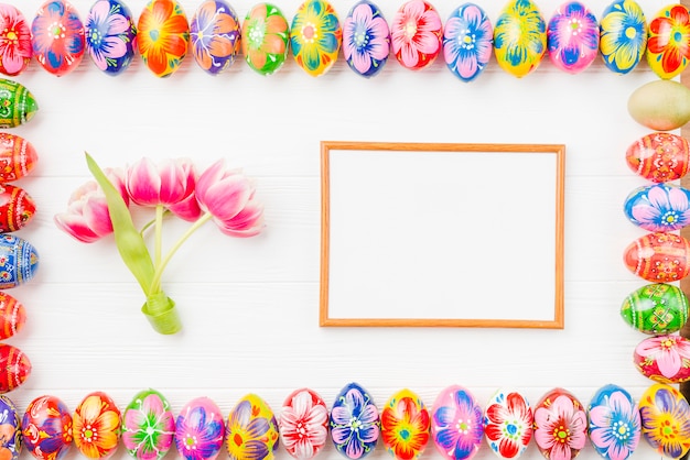Collection d'oeufs colorés sur les bords, le cadre et les fleurs Photo gratuit