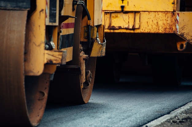Un compacteur d'asphalte jaune aligne la route. pose de nouvel asphalte. Photo Premium