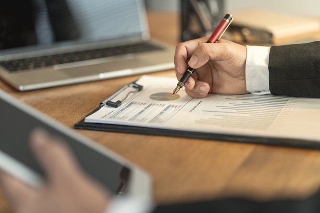 Le comptable vérifiant les documents concernant les graphiques et les tableaux relatifs aux rapports financiers et à la comptabilité fiscale de la société Photo Premium