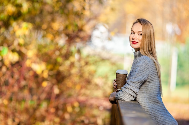 Concept de l'automne - belle femme buvant du café dans un parc en automne sous le feuillage d'automne Photo Premium