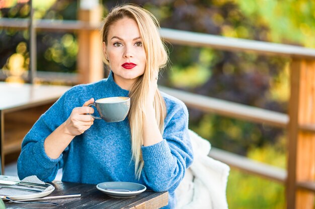 Concept de l'automne - belle femme buvant du café dans un parc en automne sous le feuillage d'automne Photo Premium