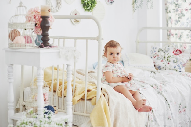 Concept D Enfance Petite Fille En Robe Mignonne Implantation Au Lit Jouant Avec Des Jouets A La Maison Chambre D Enfant Vintage Blanche Photo Premium