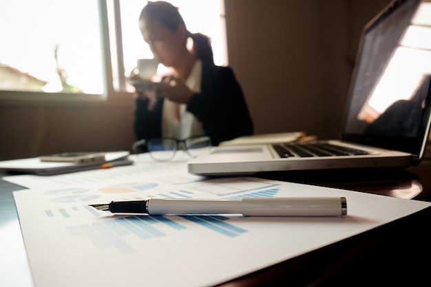 Concept d'entreprise avec espace de copie. table de bureau avec stylo et tableau d'analyse, ordinateur, ordinateur portable, tasse de café sur le bureau. tonalité de rétro filtre rétro, mise au point sélective. Photo gratuit