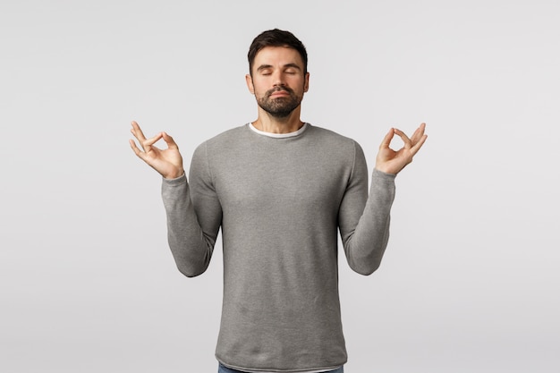 Concept De Patience, De Relaxation Et De Méditation. Paisible Jeune Beau Mec Barbu élargir L'esprit Et Le Corps, Se Sentir Zen, Lever Le Geste Mudra Des Mains, Pratiquer Le Yoga Respiratoire Avec Les Yeux Fermés Photo Premium