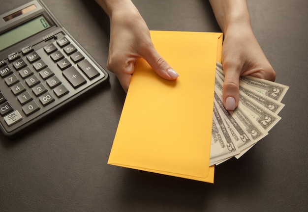 Concept de recevoir un salaire dans une enveloppe. enveloppe jaune avec de l'argent sur une table sombre. Photo Premium