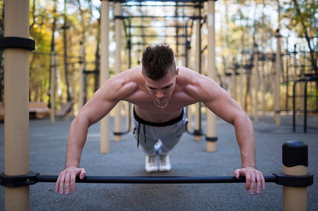 Concept de remise en forme, sport, entraînement et mode de vie - jeune adulte fit homme faisant des tractions en plein air, mode de vie sain Photo Premium