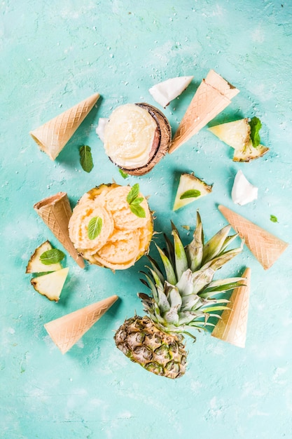 Concept de vacances d'été, définissez divers sorbets de crème glacée tropicale, jus congelés à l'ananas, au pamplemousse et à la noix de coco, béton bleu clair Photo Premium
