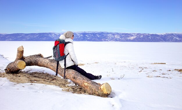 Concept de voyage. randonneuse avec sac à dos enjoing vue sur le lac baïkal, en sibérie, en russie. tourisme d'hiver. Photo Premium