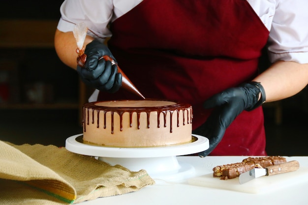 Le Confiseur Serre Le Chocolat Liquide D Une Poche A Douille Sur Un Gateau A La Creme Photo Premium