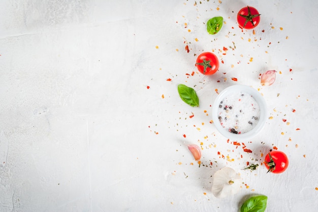 Contexte Alimentaire. Ingrédients, Légumes Verts Et épices Pour Cuisiner Le Déjeuner. Feuilles De Basilic Frais, Tomates, Ail, Oignons, Sel, Poivre. Sur Une Table En Pierre Blanche. Copier La Vue De Dessus De L'espace Photo Premium