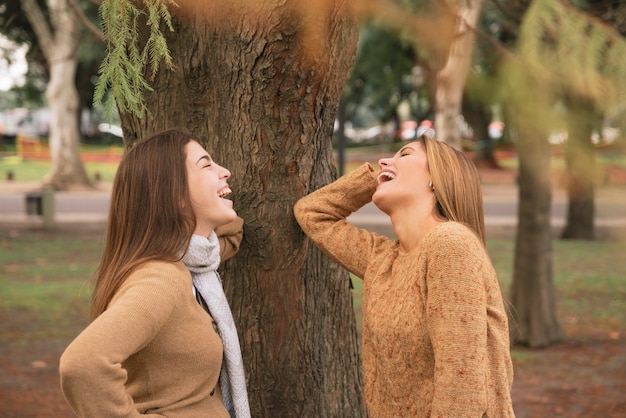 Coup moyen de deux femmes qui rient dans le parc Photo gratuit