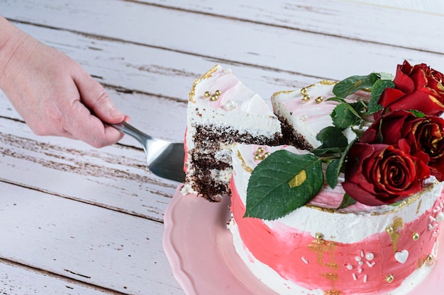 Couper Une Tranche De Gateau Au Chocolat Garnie De Creme Au Beurre A La Meringue Suisse Trois Fleurs Rouges Sur Le Dessus Photo Premium