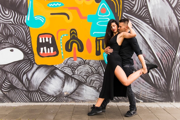 Couple affectueux dansant devant le mur de graffitis Photo gratuit