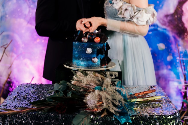 Un Couple De L Espace Coupe Un Gateau De Mariage Decore De Chocolat Et De Planetes Le Concept De Desserts Festifs Pour Les Vacances Photo Premium