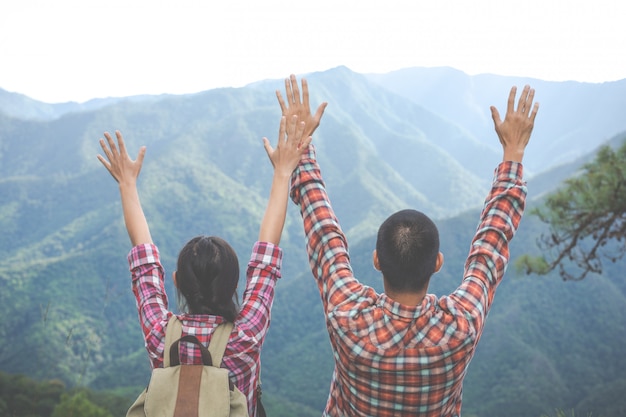 Le couple leva les mains au sommet de la colline dans la forêt tropicale. randonnée, voyages, escalade. Photo gratuit