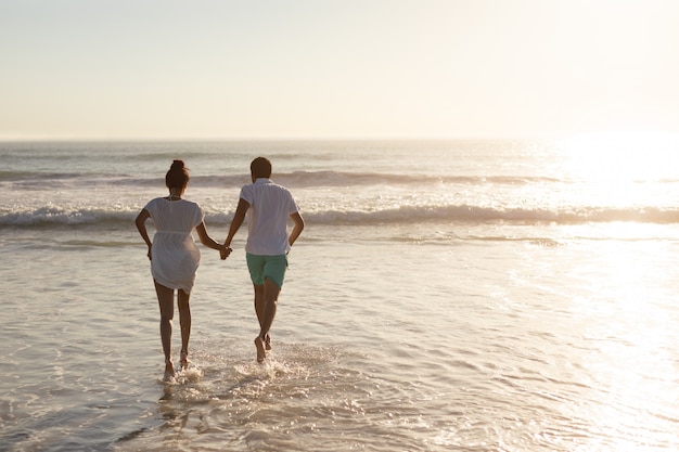 Couple s'amuser ensemble sur la plage Photo gratuit