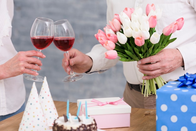 Couple De Verres A Vin Cliquetant Avec Bouquet De Fleurs De Tulipes Gateau D Anniversaire Et Coffrets Cadeaux Sur Table Photo Gratuite