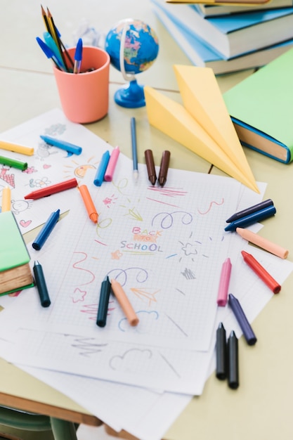 Crayons de cire colorés dispersés sur le bureau avec des dessins d'enfants Photo gratuit