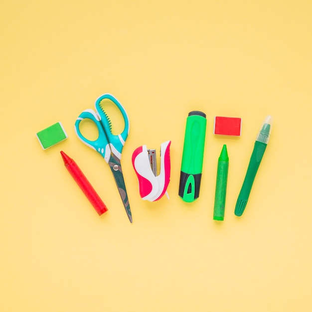 Des crayons; ciseaux; surligneur; agrafeuse et gomme disposées sur une surface jaune Photo gratuit