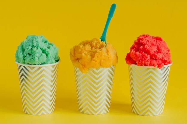 Crème glacée aux fruits verts, jaunes et rouges ou yogourt glacé dans des tasses décapées Photo Premium