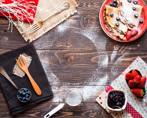 Crêpes aux fraises fraîches ou crêpes aux fruits et au chocolat sur fond en bois Photo Premium