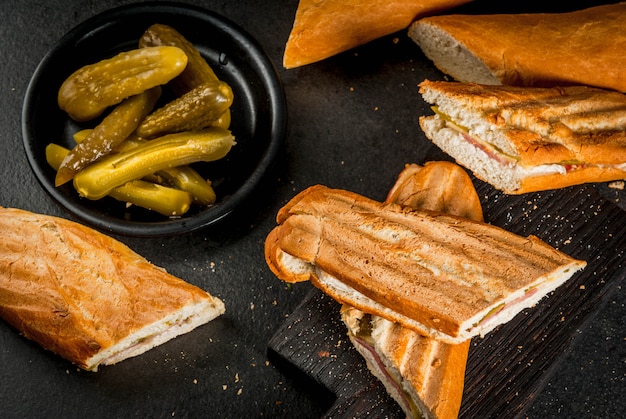 Cuisine Traditionnelle Cubaine, Collation, Nourriture De Fête. Sandwich Cubain De Baguette Avec Jambon, Porc, Fromage, Cornichons. Sur Le Fond Du Tableau Noir Photo Premium
