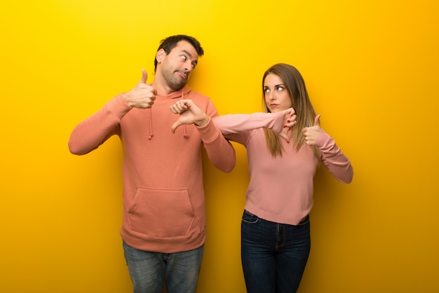 Dans la saint valentin groupe de deux personnes sur fond jaune faisant bon signe. indécis entre oui ou non Photo Premium