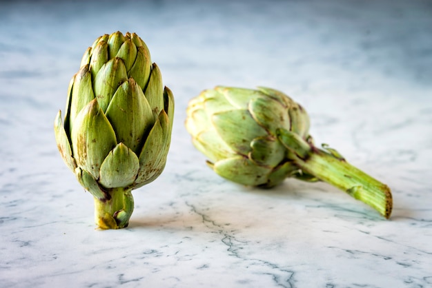 Deux artichauts frais sur un comptoir en marbre Photo Premium
