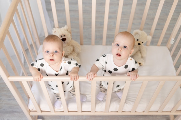 Deux Bebes Jumeaux Frere Et Sœur De 8 Mois Sont Assis En Pyjama Dans Le Berceau Et Regardent La Camera Vue Du Dessus Photo Premium